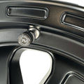 Close-up of a black valve stem cap on a black alloy wheel.