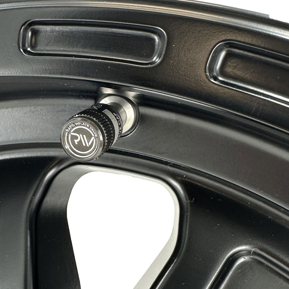Close-up of a black valve stem cap on a black alloy wheel.