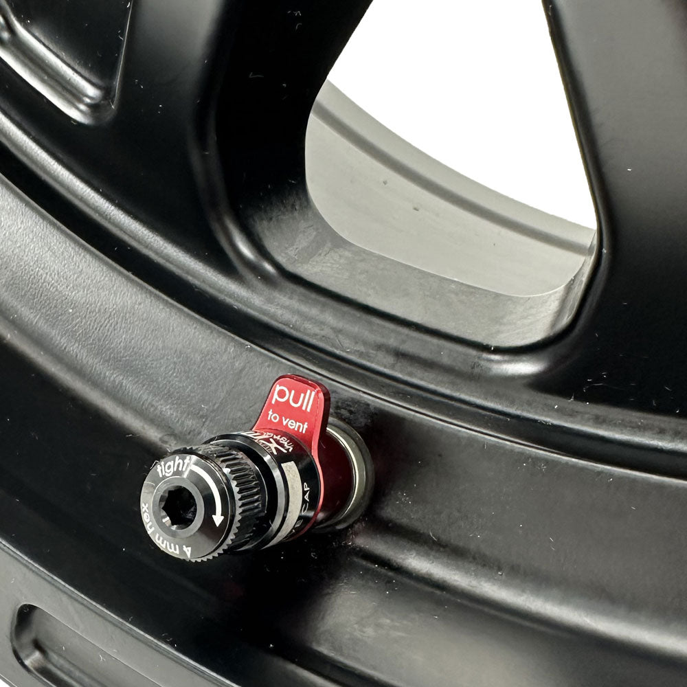 Close-up of a black wheel rim with an air release valve and pull-to-vent feature