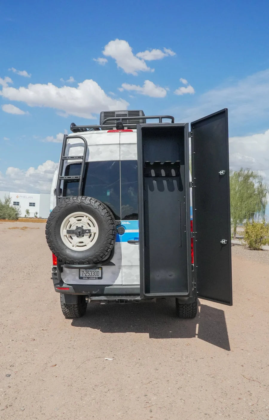 Rear view of an off-road camper van with rear doors open and a mounted spare tire.