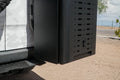 Black metal storage box mounted on the rear side of a white off-road vehicle.