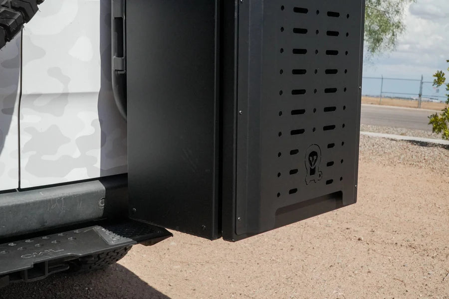 Black metal storage box mounted on the rear side of a white off-road vehicle.