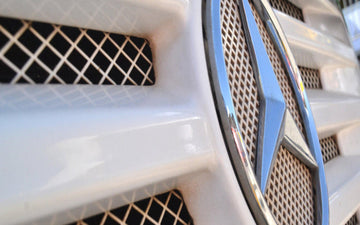 Close-up of Mercedes-Benz emblem on a white vehicle grille