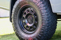 Close-up of an off-road tire with rugged tread and a black alloy wheel on a truck.
