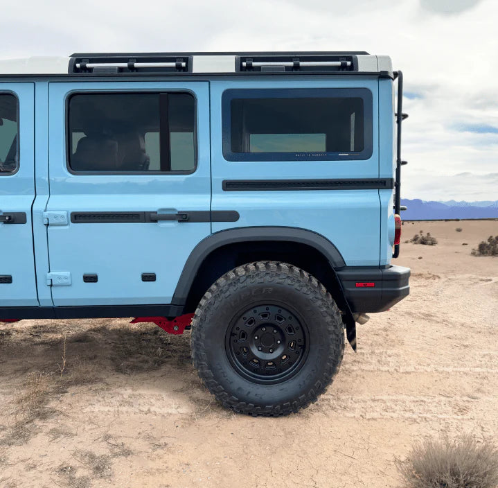 Close-up side view of a light blue off-road SUV parked on desert terrain.