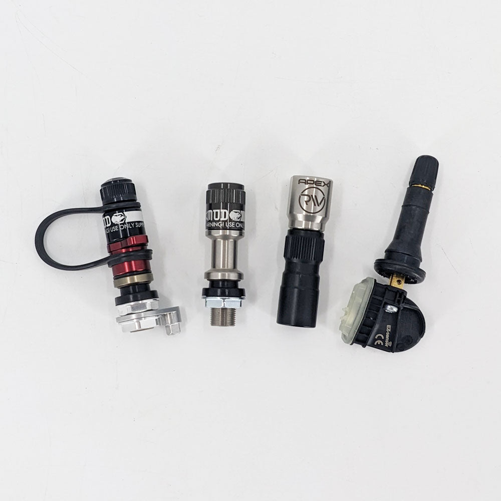 Set of four different tire valve stems and TPMS sensors on a white background
