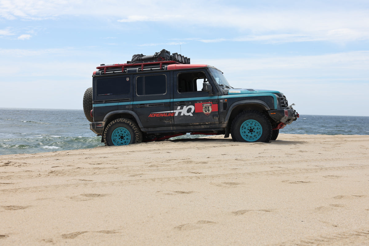 Off-road adventure vehicle parked on sandy beach near ocean