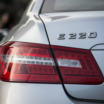 Close-up of a silver Mercedes-Benz E220 rear tail light and badge.