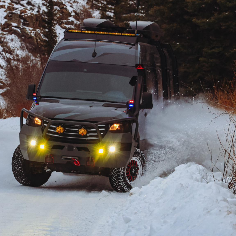 Off-road adventure van driving through snowy mountain trail at high speed